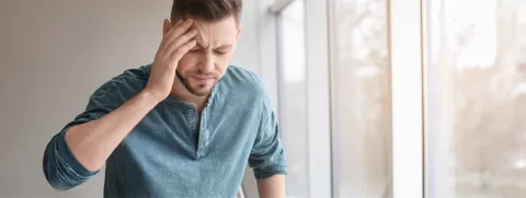 Hombre agarrándose la sien. Crisis hiertensiva.