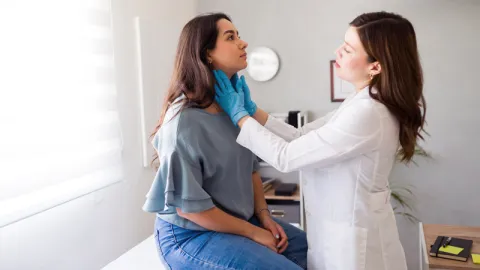 Médica revisando el cuello de una mujer. Disfagia.