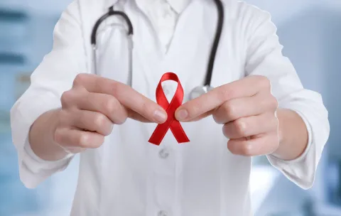 Médico sosteniendo una cinta roja con sus manos
